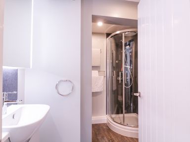 A bathroom with a white sink and chrome faucet a towel ring a glass shower enclosure and towels on a rack at Number 1 in Clare