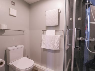 A bathroom with a toilet towels on racks and a glass shower enclosure at Number 1 in Clare