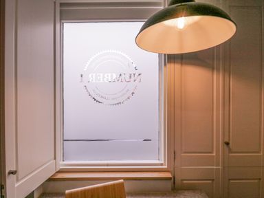 A kitchen window with frosted glass and cabinets with a hanging lamp above a countertop at Number 1 Clare