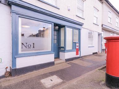A street view of a building with a blue framed window and door and two red post boxes outside at Number 1 Clare