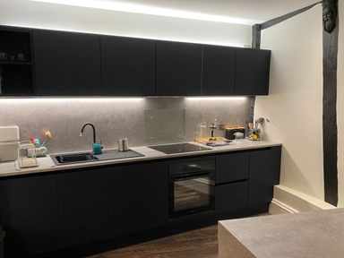 A kitchen with black cabinets a sink stovetop oven and utensils at Number 1 in Clare