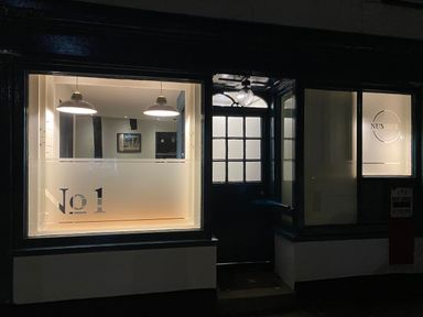 A dark exterior view of a building with illuminated windows showing a door and signage with number 1 at Number 1 in Clare
