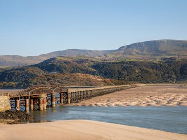 A long railway bridge crossing over a river with hills in the background at Gwynfa in Barmouth