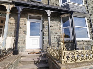 Front entrance with white door stone steps and metal railings at Gwynfa in Barmouth