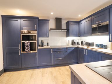 A kitchen with blue cabinets a double oven a coffee machine a toaster and a kettle at Gwynfa in Barmouth