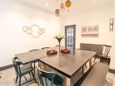 A dining room with a black table and chairs a bench and wall decorations at Gwynfa in Barmouth