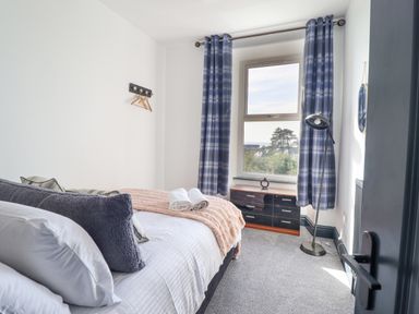 A bedroom with a bed pillows a dresser and blue check curtains at Gwynfa in Barmouth