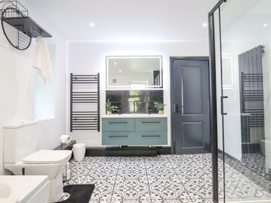 A bathroom with a toilet a towel rack a double sink vanity and a glass shower at Gwynfa in Barmouth