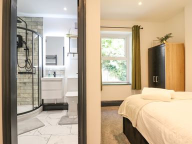 A bedroom with a bed and wardrobe next to a bathroom with a shower at Gwynfa in Barmouth