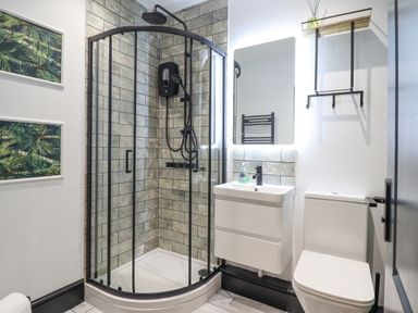 A bathroom with a corner shower enclosure sink toilet a mirror and two framed leaf artworks at Gwynfa in Barmouth