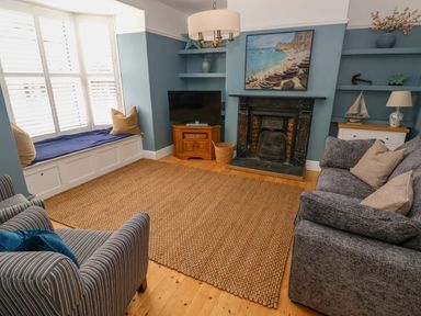 A living room with a fireplace a television a sofa an armchair and a window seat at Suffolk House in Narberth