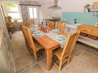 A kitchen with a wooden dining table set with plates and napkins and wooden chairs at Suffolk House in Narberth