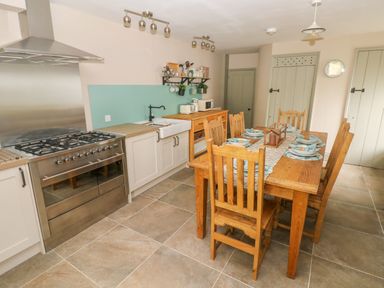 A kitchen with a dining table set with plates and napkins next to a stove and sink at Suffolk House in Narberth