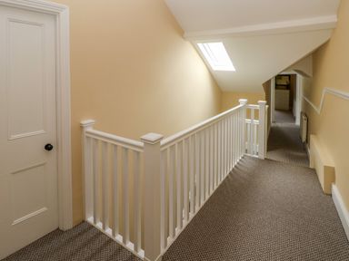 A carpeted hallway with white wooden railing and a skylight at Suffolk House in Narberth
