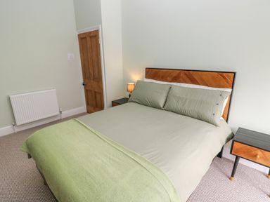 A bedroom with a double bed wooden door radiator and two bedside tables with a lamp at Suffolk House Narberth