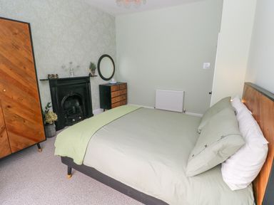 A bedroom with a bed a wooden wardrobe a chest of drawers and a fireplace at Suffolk House in Narberth