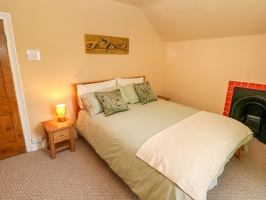 A bedroom with a bed and pillows a bedside table with a lamp and a fireplace at Suffolk House in Narberth