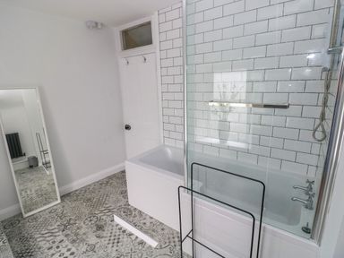 A bathroom with a bathtub shower combo and a standing mirror at Suffolk House Narberth