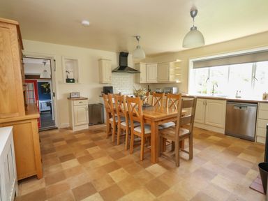 A kitchen with wooden dining table and chairs and cream cabinets at Rempstone Farmhouse in Corfe Castle