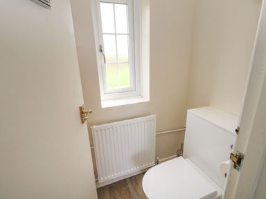 A small bathroom with a toilet radiator and a window at Rempstone Farmhouse in Corfe Castle