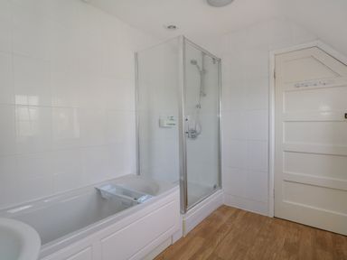 A bathroom with a bathtub shower enclosure and a white door at Rempstone Farmhouse in Corfe Castle