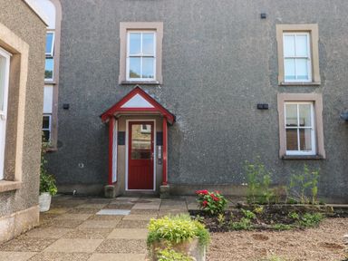 The exterior of a building with a red door and a small garden at Grassholm View in Solva