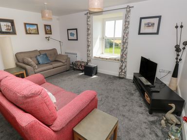 A living room with two sofas a window and a television at Grassholm View in Solva