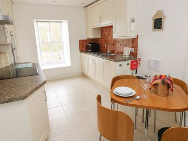 A kitchen with a window a dining table with plates glasses and a wine bucket at Grassholm View in Solva
