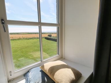A window seat with cushions overlooking a garden and fields at Grassholm View in Solva