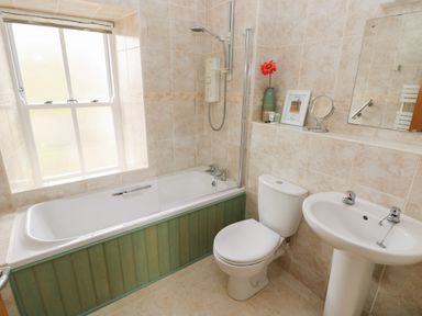 A bathroom with a bathtub shower toilet sink and a window at Grassholm View in Solva