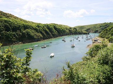 A bay with boats anchored in the water surrounded by green hills at Grassholm View in Solva