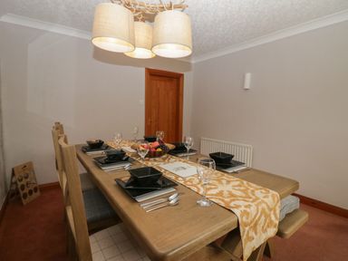 A dining room with a wooden table set for six with black tableware and a fruit bowl at 1 Gilpin House in Levens