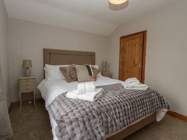 A bedroom with a double bed small bedside tables with lamps and a wooden door at 1 Gilpin House in Levens