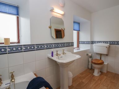 A bathroom with a pedestal sink toilet and two windows with blue blinds at 1 Gilpin House Levens