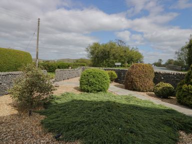 A garden with trimmed bushes gravel ground and stone walls at 1 Gilpin House in Levens