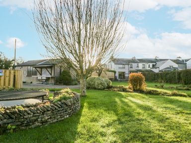 A garden with a tree and a house in the background at 1 Gilpin House Levens
