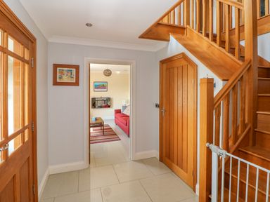 A hallway with tiled floor wooden stairs and a wooden door at Llain Gwynfor in St Davids