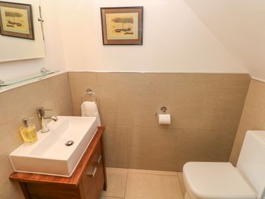 A bathroom with a sink on a wooden cabinet a toilet and a framed picture on the wall at Llain Gwynfor in St Davids