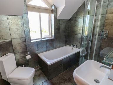 A bathroom with a toilet bathtub sink and shower with metal tiled walls at Llain Gwynfor in St Davids