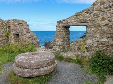 Stone ruins with a circular stone structure and a view of the ocean through an opening at Llain Gwynfor in St Davids