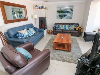 A living room with two sofas an armchair a wooden coffee table a rug a fireplace and a television at Llain Gwynfor in St Davids