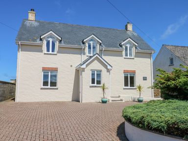 A two story house with three dormer windows and a paved driveway at Llain Gwynfor in St Davids
