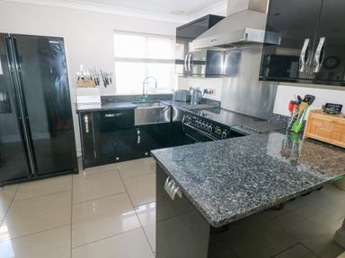 A kitchen with black cabinets granite countertops a double sink refrigerator stove and various utensils at Llain Gwynfor in St Davids