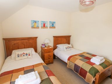 A bedroom with two single beds and a wooden nightstand in the middle at Llain Gwynfor in St Davids
