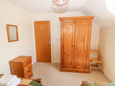 A bedroom with a wooden wardrobe a wooden chest of drawers a wooden chair and a wooden door at Llain Gwynfor in St Davids