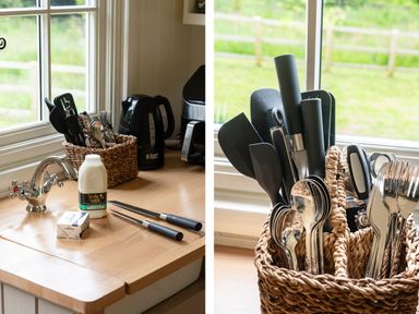 A kitchen counter with cutlery in a wicker basket knives a kettle and a bottle of milk at Bedwen in Aberaeron