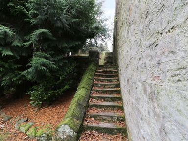 An outdoor stone stairway covered with leaves next to a stone wall and trees at The Folly in Belford