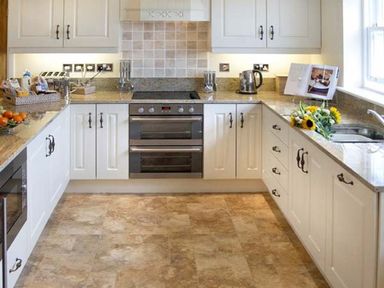A kitchen with white cabinets an oven a sink a kettle flowers and a cookbook near The Lake Cottage Near Belford