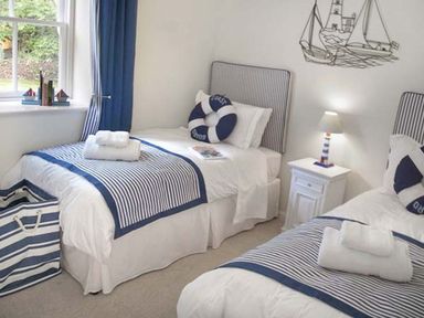 A bedroom with two single beds striped bedding and a nightstand with a lamp at The Lake Cottage Near Belford