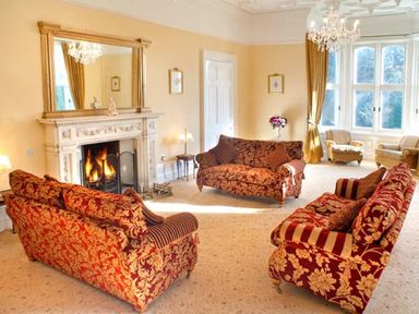 A living room with patterned sofas a fireplace and large windows at The Hall in Belford